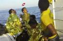 In this image made from video provided by the Italian Coast Guard and recorded on Thursday, Oct. 3, 2013, survivors of a ship transporting hundreds of migrants which caught fire and sank wear thermal rescue blankets after being rescued by the Italian Coast Guard off the Sicilian island of Lampedusa, Italy. Authorities on Friday, Oct. 4 are contending with choppy waters in the search for dozens of migrants believed to have drowned after their rickety boat caught fire and sank off the coast of the southern Italian island of Lampedusa. (AP Photo/Italian Coast Guard)