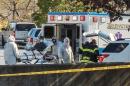 Ambulance workers wearing protective gear load a patient with possible Ebola symptons into the back of an ambulance at the Harvard Vanguard facility in Braintree