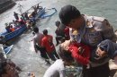 A police officer carries an unconscious child who was on the boat that capsized late on Tuesday after hitting a reef off the coast of Sukapura, in Cianjur