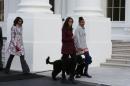 U.S. first lady Obama walks out with her daughters and the family dogs to receive the official White House Christmas tree in Washington
