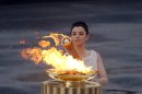 High priestess Ino Menegaki lights the torch with the Olympic Flame, during a handover ceremony for the Olympic flame at Panathenaean stadium in Athens, Thursday, May 17, 2012. The torch begins its 70-day journey to arrive at the opening ceremony of the London 2012 Olympics, from the Greek capital, to cover about 8,000-mile (12,875-kilometer) on its progress over many parts of England to start the games. (AP Photo/Kostas Tsironis)