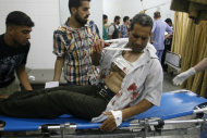 Palestinians bring a wounded man to the treatment room of Al Najar Hospital following an Israeli airstrike in Rafah, southern Gaza Strip, Monday, June 18, 2012. Palestinian medics said five Palestinians were wounded during the airstrike on a metal workshop. The Israeli military said a weapon manufacturing facility was targeted during the airstrike. (AP Photo/Eyad Baba)
