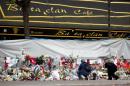 People mourn in front of the screened-off facade of the Bataclan Cafe adjoining the concert hall, one of the sites of the deadly attacks in Paris