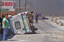 A South African Police truck, left, that was overturned by farm workers after they went on a rampage in Wolseley, South Africa, Wednesday, Nov. 14, 2012. Violent protests by farm workers have erupted in South Africa after weeks of unrest in the country's mining industry. Television images showed protesters overturn a police truck and set fires in the streets Wednesday in a town in South Africa's Western Cape. The workers have been protesting their wages, saying they want a minimum wage of $17 a day. Currently, workers make about half that amount a day. (AP Photo)