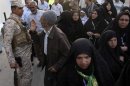 Iranian Shi'ite Muslim pilgrims walk past a member of Iraq's security personnel in Kerbala