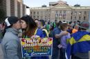 With the Arizona Capitol in the background, gay rights supporters Rachel Butas, right, and Jo Jo Halko kiss after the two learn that Arizona Gov. Jan Brewer announces she has vetoed SB1062, a bill designed to give added protection from lawsuits to people who assert their religious beliefs in refusing service to gays, on Wednesday, Feb. 26, 2014, in Phoenix. (AP Photo/Ross D. Franklin)