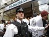 A police officer controls demonstrators outside a Starbucks coffee shop in central London