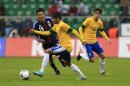 Brazil's Oscar watches team mate Neymar runs ball past Japan's Konno during friendly soccer match in Wroclaw