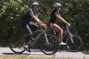 President Barack Obama bike rides with daughter Malia Obama on the Manuel F. Correllus State Forest bike path, Friday, Aug. 15, 2014, outside of West Tisbury, Mass., during the Obama family vacation on the island of Martha's Vineyard. (AP Photo/Jacquelyn Martin)