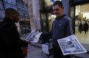 A man takes a copy of an evening newspaper, which features an article about Lord Justice Brian Leveson's report on media practices on its front page, from a distributor in central London