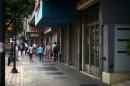 People walk past closed shops in a street of Caracas on March 22, 2016