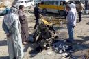 Iraqis look at the remains of a vehicle following an explosion at the Mashtal district of Baghdad, on October 27, 2013