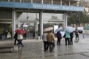 Cypriots walk outside Bank of Cyprus branch on the island's capital Nicosia