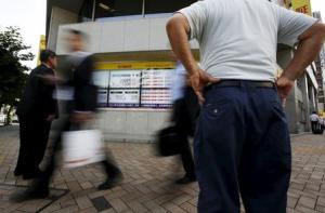 Passersby walk past an electronic stock quotation board outside a brokerage in Tokyo