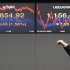 A currency trader stretches in front of the Korea Composite Stock Price Index (Kospi), left, and the exchange rate between the U.S. dollar and South Korean won at the Korea Exchange Bank headquarters in Seoul, South Korea, Tuesday, Jan. 10, 2012. Asian stocks rose Tuesday, tracking slight gains on Wall Street and assisted by an absence of bad financial news. South Korea's Kospi rose 1.46 percent, or 26.73 points, to close at 1,853.22. (AP Photo/Ahn Young-joon)