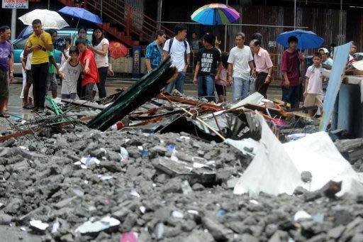 People look at debris after a wall collapsed as super-typhoon Nanmadol moved throughQuezon City, east of Manila