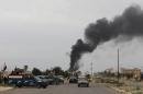 Smoke rises from buildings as Iraqi security forces patrol a street in Tikrit, on April 1, 2015