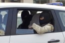 An unidentified man with his head covered, believed to be Abdelkader Merah or his companion, sits between masked police officers as they head to the French police's anti-terrorist headquarters in Levallois-Perret, outside Paris, Saturday, March 24, 2012. Merah's brother, Mohamed Merah is blamed for a series of deadly shootings which have shocked France and upended the country's presidential race. Merah, who claimed allegiance to al-Qaida, died in a hail of gunfire Thursday after a dramatic 32-hour-long standoff with law enforcement. (AP Photo/Christophe Ena)
