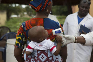 Profissional de saúde verifica a temperatura de um bebê entrar Mali da Guiné na fronteira em Kouremale