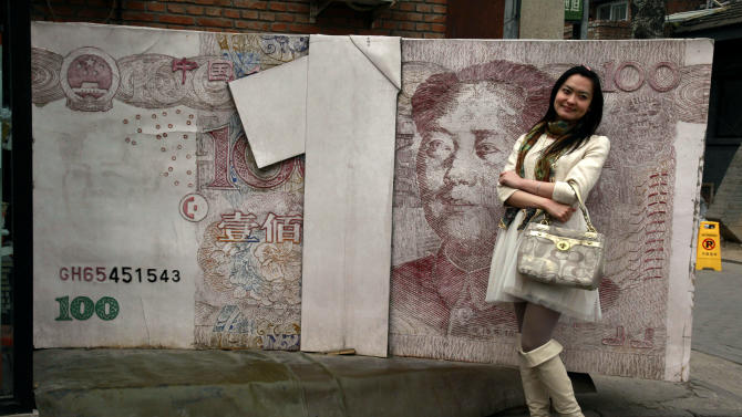 FILE - In this March 15, 2012 file photo, a Chinese woman poses for photos near a sculpture depicting a Chinese yuan note at an art district in Beijing, China. China devalued its tightly controlled currency on Tuesday, Aug. 11,2015,  following a slump in trade, triggering the yuan&#39;s biggest one-day decline in a decade.  The central bank said the yuan&#39;s 1.3 percent fall was due to a change aimed at making its exchange rate controls more market-oriented. But any change raises the risk of tensions with China&#39;s trading partners. (AP Photo/Ng Han Guan, File)