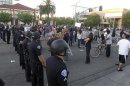 Police officers from Orange County in riot gear walk towards protesters attempting to occupy the corner of Anaheim Blvd. and Broadway to demonstrate against recent police shootings in Anaheim