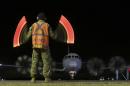 A ground crewman guides a RAAF AP-3C Orion along the tarmac as it returns from the search for missing Malaysia Airlines Flight MH370 in Perth, Australia, Sunday, March 30, 2014. Australia's Prime Minister Tony Abbott said Sunday he was hopeful clues will emerge soon to help find Flight 370 even though searchers again failed to find jet debris, as relatives of Chinese passengers on the plane protested in Malaysia to demand the government apologize over its handling of the search. (AP Photo/Rob Griffith)