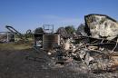 The charred remains of a trailer home are left on Monday, May 5, 2014 in Guthrie, Okla., the day after a wildfire tore through the area. Firefighters worked through the night and into early Monday to battle the large wildfire that destroyed at least six homes and left at least one person dead after a controlled burn spread out of control in central Oklahoma.(AP Photo/Nick Oxford)