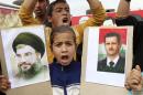A Syrian refugee girl shout slogans as she holds pictures of Syria's President Assad and Lebanon's Hezbollah leader Nasrallah during a celebration at Marj al-Khokh refugee camp near Marjayoun village