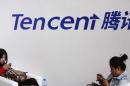 Visitors use phones underneath of logo of Tencent at Global Mobile Internet Conference in Beijing