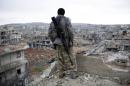 In this picture taken Friday, Jan. 30, 2015, a Syrian Kurdish sniper looks at the rubble in the Syrian city of Ain al-Arab, also known as Kobani. The Islamic State group has acknowledged for the first time that its fighters have been defeated in the Syrian town of Kobani and vowed to attack the town again. (AP Photo)