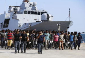 Migrants disembark from an Italian navy vessel in the Sicilian harbour of Augusta