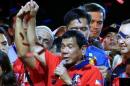 Philippine presidential candidate and Davao city mayor Rodrigo 'Digong' Duterte raised his arm by a supporter during a "Miting de Avance" before the national elections at Rizal park in metro Manila