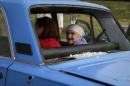 An old woman sits in a car with bullet holes and shattered windows as she flees fighting in the eastern Ukrainian town of Slaviansk
