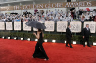 FILE- In this Sunday, Jan. 17, 2010, file photo, a publicist walks down the red carpet as it rains before the 67th Annual Golden Globe Awards in Beverly Hills, Calif. A federal judge ruled on April 30, 2012, that a $150 million agreement keeping the Globes on NBC is valid, siding with the show’s longtime producers and against the organization that organizes the glitzy awards gala each year. (AP Photo/Chris Pizzello, File)