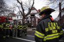 Firefighters stand in front of a house that caught fire after a portable cooker malfunctioned on March 21, 2015 in New York