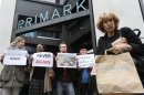 A shopper passes demonstrators outside clothing retailer Primark in central London