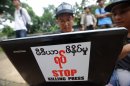 A Myanmar journalist works on his laptop carrying a sticker reading, "Stop Killing Press" in Yangon on August 23, 2012