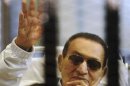 Former Egyptian President Mubarak waves inside a cage in a courtroom at the police academy in Cairo