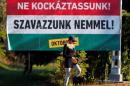Woman walks with her dog in front of the Hungarian goverment's referendum poster regarding EU migrant quotas in Budapest