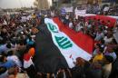 Iraqi protesters deploy a giant national flag during a demonstration against corruption and to express support for Prime Minister Haider al-Abadi's reform plan aimed at curbing corruption on August 28, 2015 in Karbala