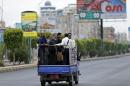 People ride on the back of a truck taxi in Yemen's capital Sanaa