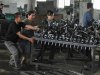 Workers push a cart carrying automobile components at a car parts plant in Shenyang