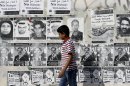 A Bahraini boy walks by a wall with signs in English and Arabic objecting to a government-mediated dialogue scheduled for Sunday between opponents and supporters of the Bahraini monarchy in Sitra, Bahrain, on Saturday, Feb. 9, 2013. Bilingual posters on the wall are honoring those who have died in recent unrest, condemning U.S. President Barak Obama and British Prime Minister David Cameron, and promoting the street demonstration plans of the Feb. 14 youth group on the upcoming second anniversary of Bahrain's pro-democracy uprising. (AP Photo/Hasan Jamali)