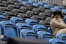 A spectator sits next to a section of empty seats during the equestrian eventing dressage phase at the 2012 Summer Olympics, Sunday, July 29, 2012, in London. (AP Photo/David Goldman)