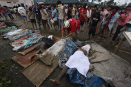 A rescuer covers bodies recovered from flashflood in New Bataan, Compostela Valley province, southern Philippines Wednesday, Dec. 5, 2012. The death toll from Typhoon Bhopa climbed to more than 100 people Wednesday, while scores of others remain missing in the worst-hit areas of the southern Philippines. (AP Photo/Karlos Manlupig)