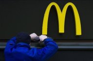 A worker drills a hole underneath the McDonald's brand sign at a store of the global fast food chain in Berlin February 15, 2012. REUTERS/Thomas Peter