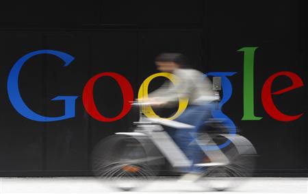 An employee rides her bike past a logo next to the main entrance of the Google building in Zurich in this July 9, 2009 file photo. REUTERS/Christian Hartmann/Files