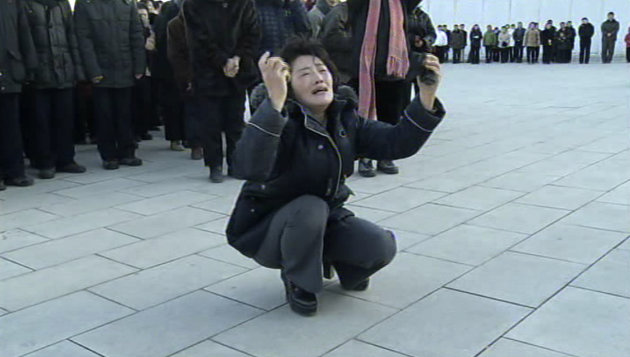 In this image made from Associated Press Television News, a woman reacts as North Koreans gather to mourn the death of North Korean leader Kim Jong Il in front of a monument to his father, Kim Il Sung