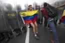 A protester with a Venezuelan flag is pushed away by National Guard soldiers trying to keep demonstrators from reaching the National Electoral Council (CNE) in Caracas, Venezuela, Wednesday, May 11, 2016. The opposition is marching against the country's administration, demanding that election officials start counting signatures that could lead to a presidential recall vote. (AP Photo/Ariana Cubillos)