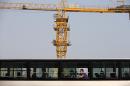 A man yawns in a bus which drives past a construction site in Beijing, China Tuesday, April 29, 2014. The International Monetary Fund raised its economic growth forecast for China on Monday but warned that its financial system faces risks due to the rapid expansion of debt. (AP Photo/Andy Wong)
